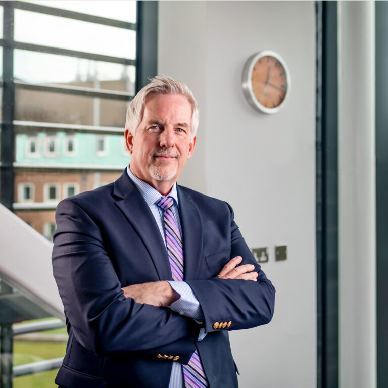 Picture of Rob Bristow inside the Manchester Cancer Research Centre.  Arms folded looking towards the camera. 