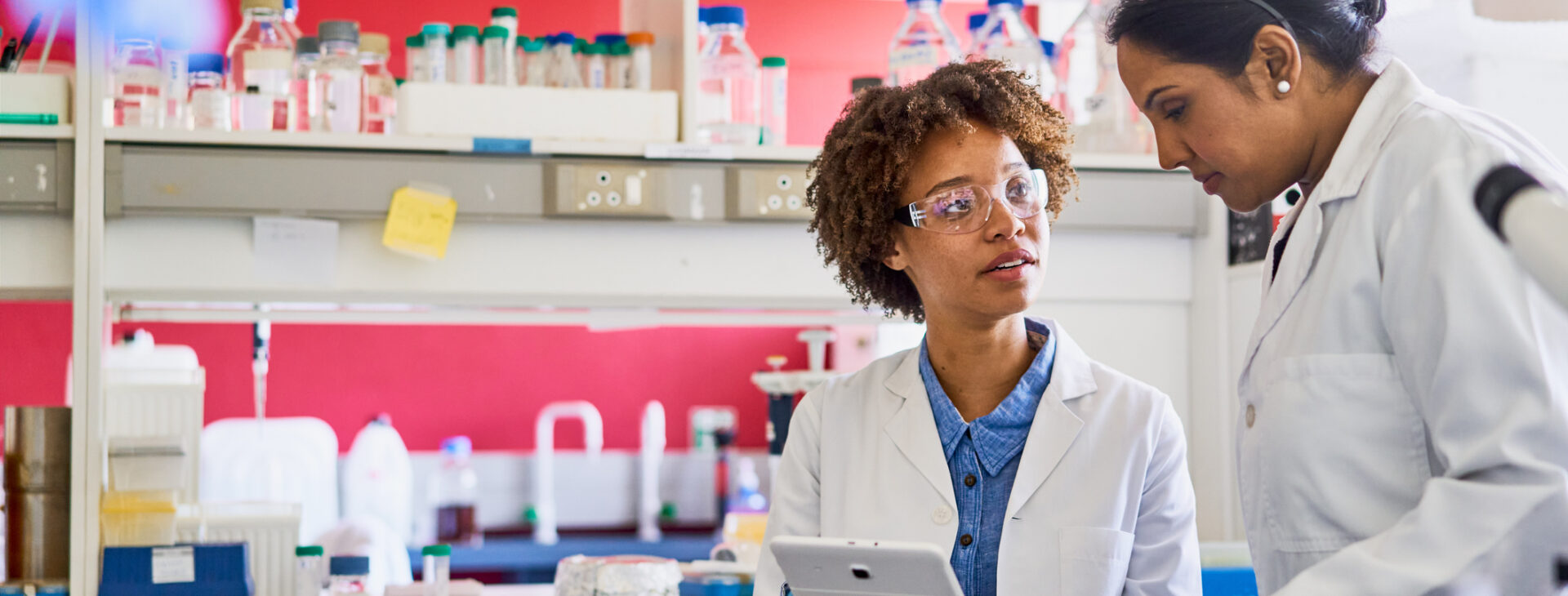 Two scientists using a digital tablet in a lab