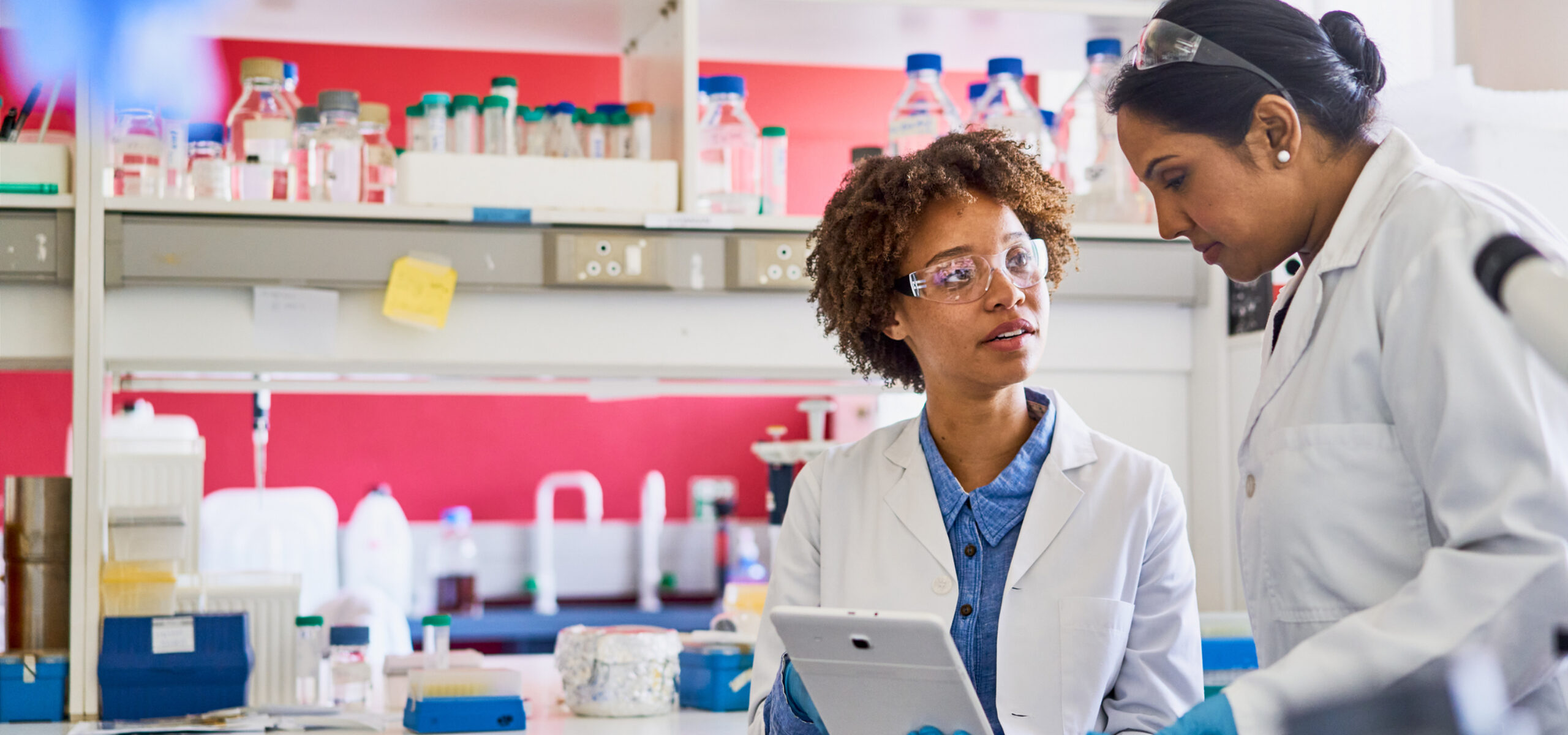 Two scientists using a digital tablet in a lab