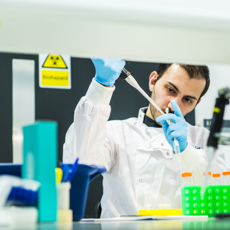 A researcher using a pipette in a laboratory