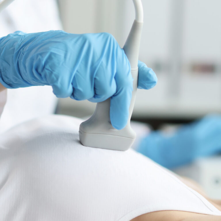 Doctor doing ultrasound examination of breast of patient in clinic